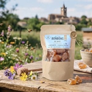 Sachet kraft 50g de bonbons au miel artisanal Le Monde des Zab'eilles posé sur un plateau en bois à Daux.